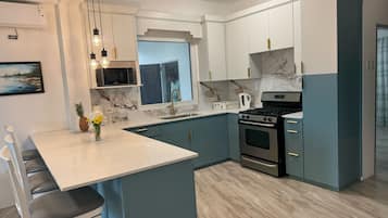 A modern kitchen with a central island, built-in appliances, and a view to the outside.