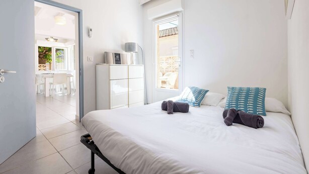A bedroom with a bed, pillows, a bedside table, a wardrobe, and a door leading to a balcony. - Le Patio de la Mer – Comfortable one-bedroom flat with terrace in Valras-Plage (Valras-Plage)