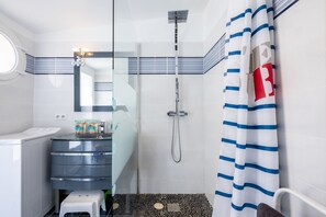 Ein modernes Badezimmer mit Duschkabine aus Glas, einem weißen Waschbecken und einer gestreiften Duschvorhang.
