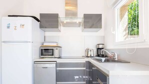 A compact kitchen with a refrigerator, microwave, coffee maker, and a dishwasher. - Le Patio de la Mer – Comfortable one-bedroom flat with terrace in Valras-Plage (Valras-Plage)