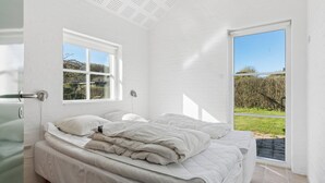 Un dormitorio con una cama, una ventana y una puerta que da a un espacio exterior.