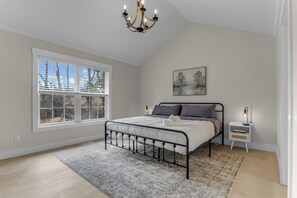 A bedroom with a bed, a window, a chandelier, a nightstand, and a painting. - Sleep 9 Boiling Springs SC w/2 kings, Pool Table (Boiling Springs)
