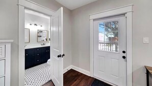 A hallway with a white door, a white-framed mirror, and a dark-colored cabinet. - Spacious Getaway | Cozy & Modern | Backyard Dream (Tampa)