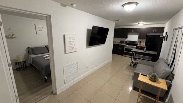 Un apartamento moderno con kitchenette, comedor y sala de estar con sofá y una mesita.