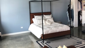 Una camera da letto con un letto a baldacchino, una ventola a soffitto, un armadio e un divano in pelle.
