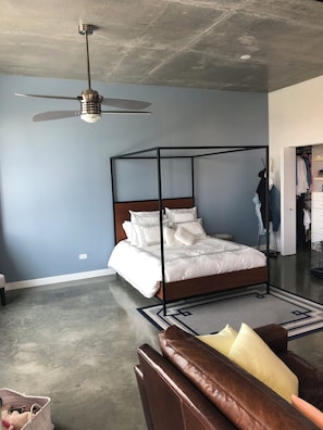 Ein Schlafzimmer mit einem Himmelbett, Deckenventilator, Schrank und einer Ledersofa.