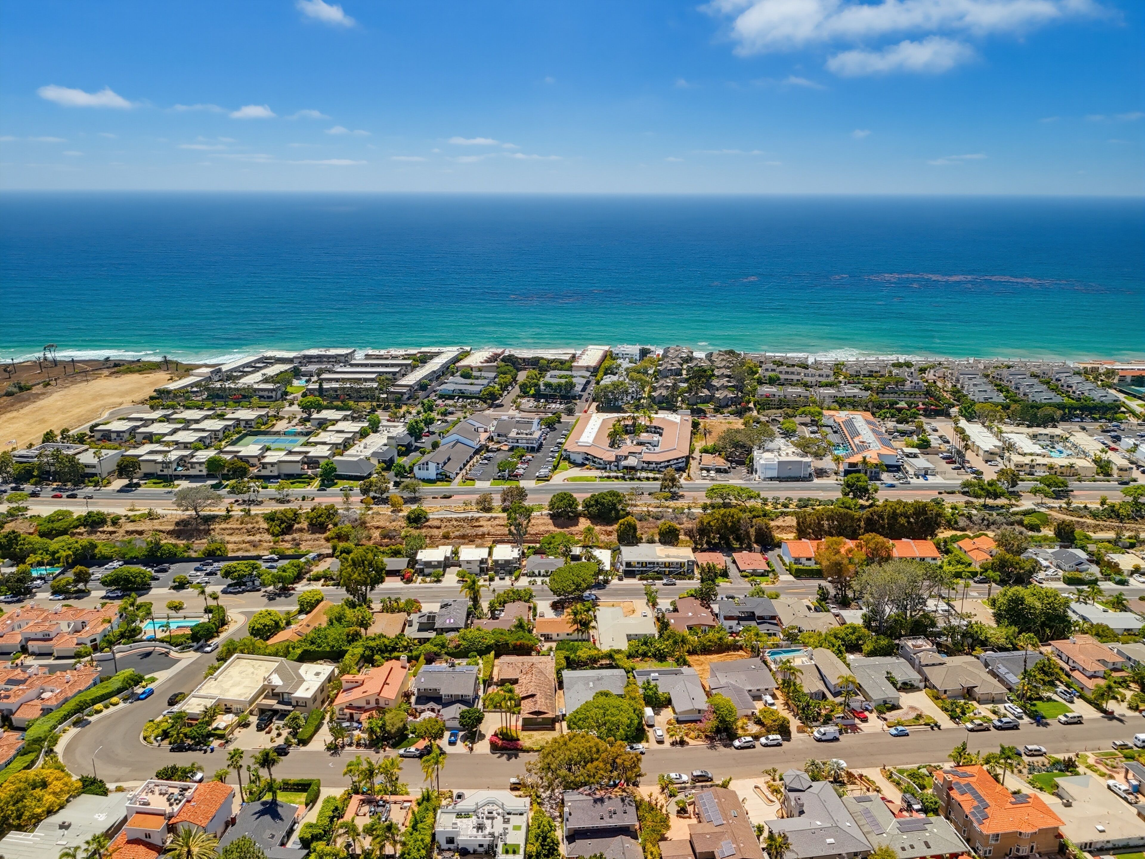 An aerial view of a coastal residential area with houses, roads, and a beach.
