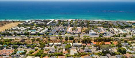 An aerial view of a coastal residential area with houses, roads, and a beach.
