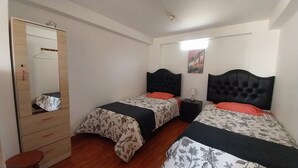 Een slaapkamer met twee bedden, een garderobe, een spiegel en een nachtkastje.