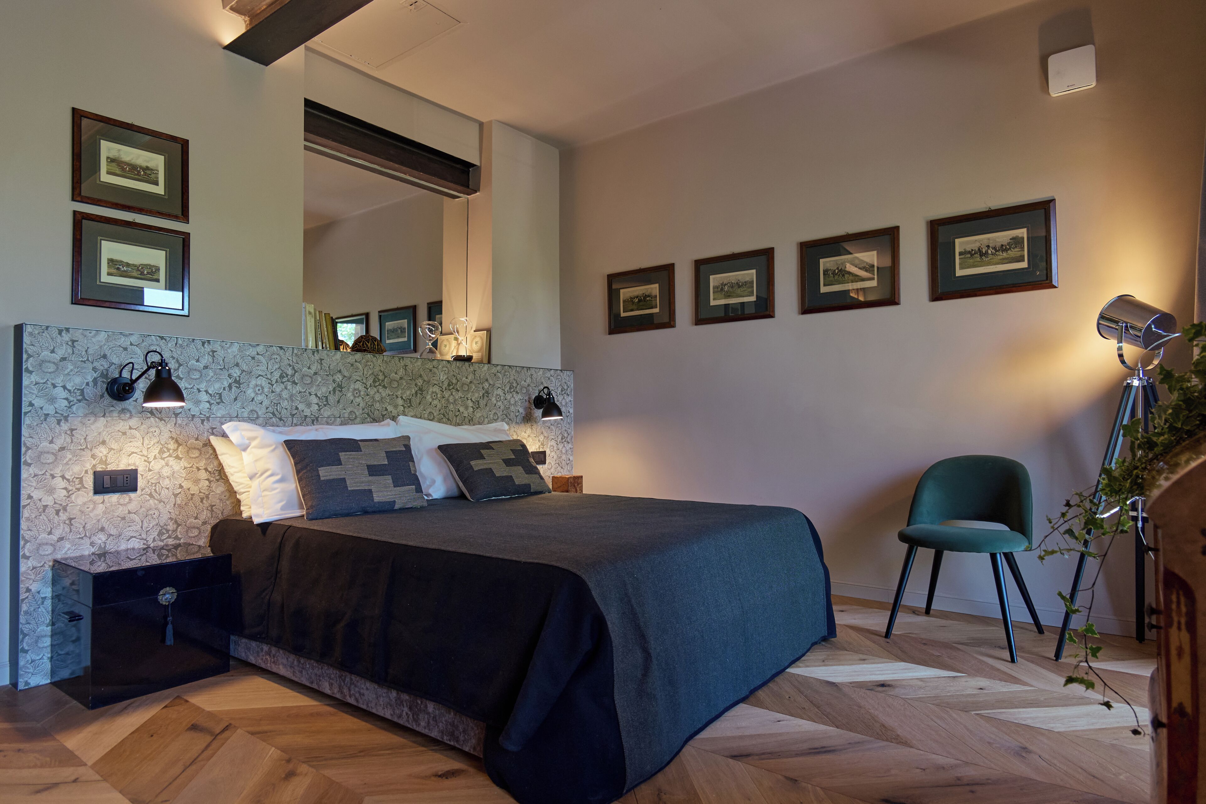 Een slaapkamer met een bed, nachtkastjes, een stoel, een spiegel en foto's in lijsten aan de muur.