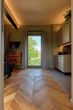 A modern kitchen with a large window, a flat-screen TV, and a herringbone wood floor.