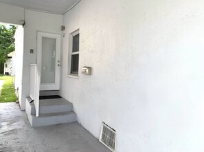 A white exterior wall with a door, a window, and a small vent. - Cozy Studio Near Coral Gables | Perfect for 2 (Miami)