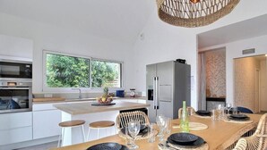 Una cucina moderna con isola centrale, mobili bianchi e un'ampia finestra.