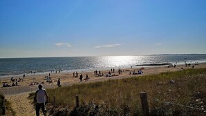 Una spiaggia con persone, cielo sereno e oceano.