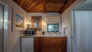 Ein kleines Badezimmer mit Holzboden, einer Mikrowelle, einem Waschbecken und einem kleinen Kühlschrank.