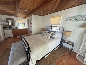 Une chambre à coucher avec un lit, une table de chevet et une vue sur la cuisine.