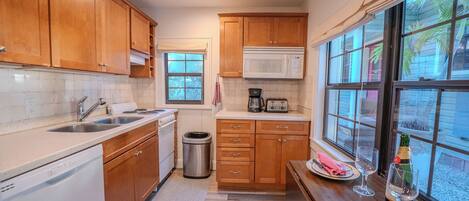 Cocina compacta con muebles de madera, microondas, tostadora y ventana con vista al exterior.