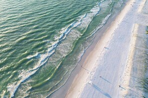 Vue aérienne d’une plage où les vagues se rapprochent du rivage.
