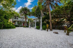 A house with a gravel driveway, surrounded by palm trees and other vegetation. - On the Beach…Retreat on the Sand—2 Units upstairs and downstairs, Sleeps 6 (Indian Rocks Beach)