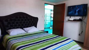 Ein Schlafzimmer mit einem Bett, einem an der Wand montierten Fernseher und einer Tür, die auf einen Balkon führt.