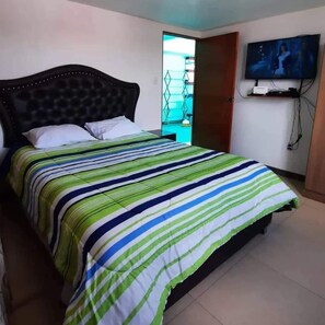 Ein Schlafzimmer mit einem Bett, einem an der Wand montierten Fernseher und einer Tür, die auf einen Balkon führt.