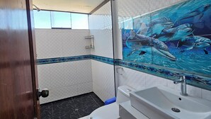 Ein Badezimmer mit Dusche, Toilette, Waschbecken und einer großen Wandmalerei mit Unterwasserlebewesen.