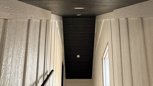 A wooden staircase with a black handrail leading to a landing. - Bozeman Getaway Guesthouse - Suite C (Bozeman)