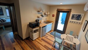 A compact kitchen with a microwave, sink, and small dining area with chairs. - Bozeman Getaway Guesthouse - Suite C (Bozeman)