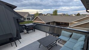 A rooftop patio with a grill, seating, and a view of neighboring houses. - Bozeman Getaway Guesthouse - Suite C (Bozeman)