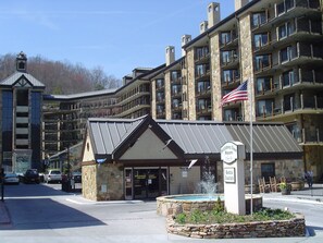 A multi-story hotel with a stone facade, a flag, and a sign indicating availability of rentals. - 1-bedroom resort in Gatlinburg Town Square, Tennessee with AC and fitness room (Gatlinburg)