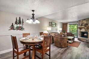 A dining area with a round table and chairs, a fireplace, and a sofa in a living room. - 1-bedroom resort in Gatlinburg Town Square, Tennessee with AC and fitness room (Gatlinburg)