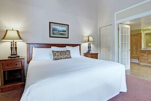 A hotel room with a large bed, two bedside tables with lamps, a framed picture on the wall, and a door leading to a bathroom. - 1-bedroom resort in Gatlinburg Town Square, Tennessee with AC and fitness room (Gatlinburg)