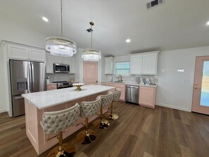 A modern kitchen with stainless steel appliances, a marble countertop, and a central island with bar stools. - Girl's Night Out - WinStar Bachelorette - King Bed (Love County)
