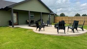 A house with a covered patio area featuring outdoor furniture and a wooden fence in the background.