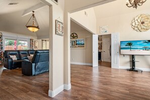 A spacious living room with a leather sofa, wooden flooring, and a dining area with a table and chairs. - Cheerful Oasis w/ Private Hot Tub, Yard, & Big Rooms (Fort Worth)