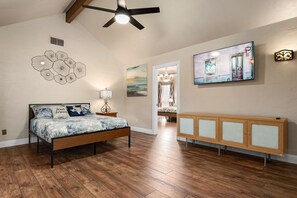 A bedroom with a bed, wooden flooring, a ceiling fan, wall art, and a cabinet. - Cheerful Oasis w/ Private Hot Tub, Yard, & Big Rooms (Fort Worth)