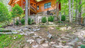 Une cabane en bois, construite sur des fondations en pierre, et entourée d’une forêt.