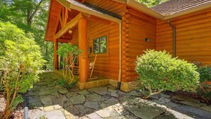 Une cabane en bois avec un chemin de pierre menant à l’entrée, entourée de verdure.