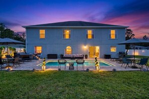 A two-story building with a swimming pool, outdoor seating, and a well-lit entrance. - Ultimate Coastal 6BR Home w/ Private Pool & Hot Tub | Near Flagler Beach | Palm Coast | Sleeps 10+ (Palm Coast)