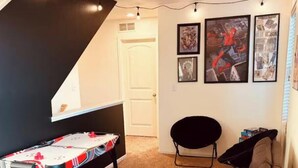 Ein Wohnzimmer mit einer Couch, einem Spieltisch und Wandkunst.