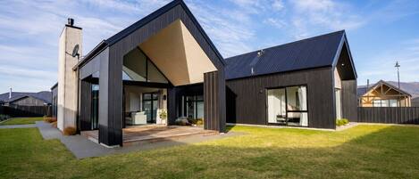 A modern two-story house with a large front porch, a chimney, and a well-maintained lawn.