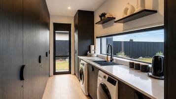 A modern kitchen with a built-in washer and dryer, a large window, and a view of the backyard.