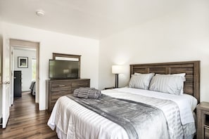 A bedroom with a bed, a dresser, a television, and a lamp.