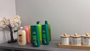 Une étagère contenant divers produits de toilette, notamment un gel douche Irish Spring et un savon au lait et au miel.