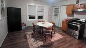 Une cuisine de taille réduite comprenant une table à manger, des chaises, un réfrigérateur, un four et des placards.