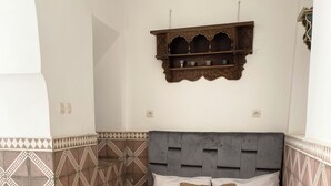 Quarto com cama, paredes estampadas, prateleira decorativa e tapete padronizado.