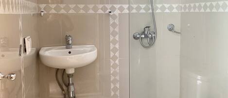 A bathroom with a glass-enclosed shower, a sink, and a mirror.
