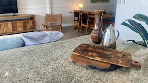 Een woonkamer met een televisie, houten meubels, een vaas, een koffiezetapparaat en een plant.