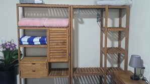 Un letto a castello in legno con cassettiere e ripiani, un tavolino con una lampada e una pianta in vaso.