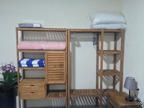 Ein hölzernes Etagenbett mit Stauraumschubladen und Regalen, ein kleiner Tisch mit Lampe sowie ein Topfpflanze.